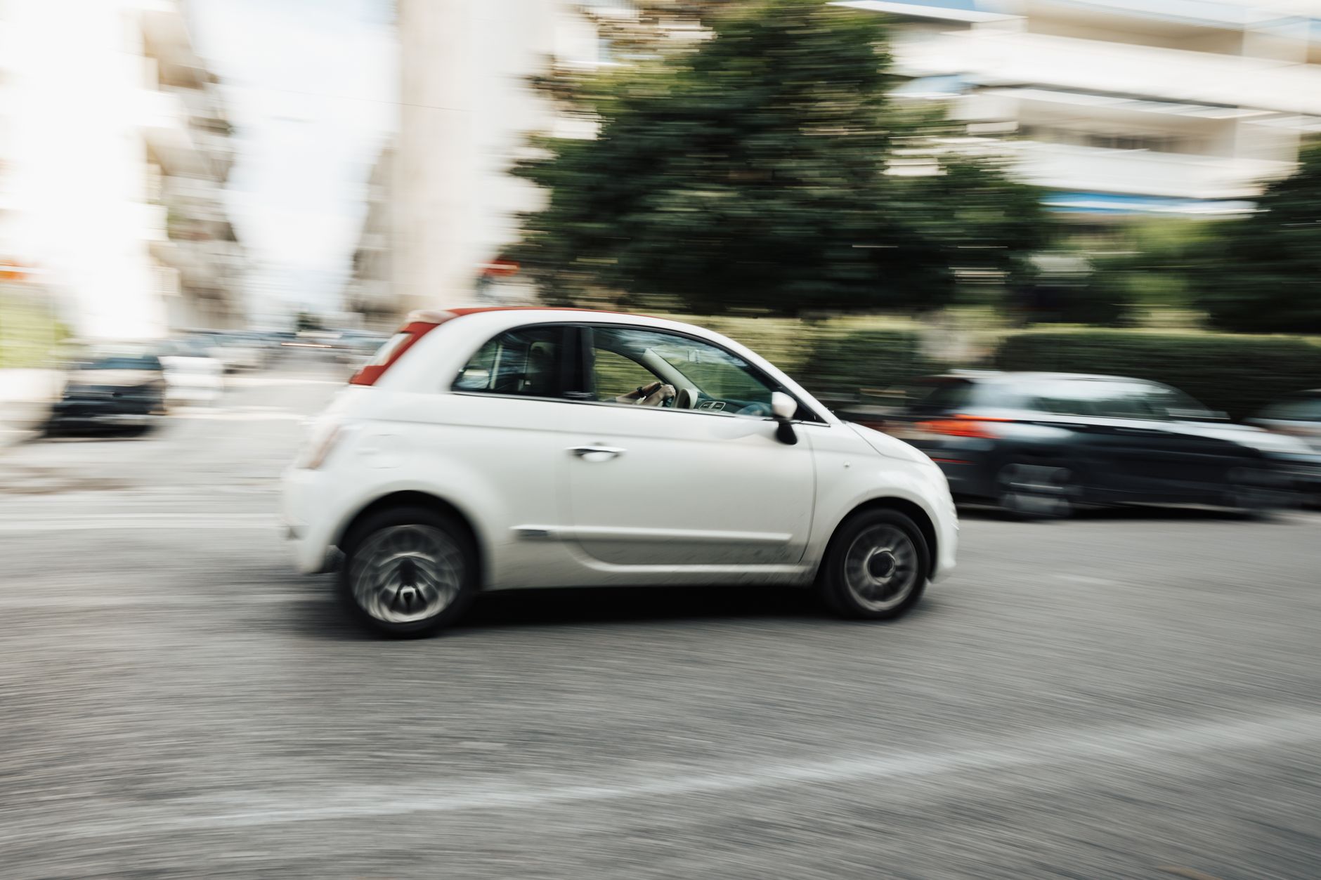 Białe miejskie auto pędzące ulicą, rozmyte tło miasta