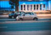 Fiat 500 jedzie nocą obok nowoczesnego, niebiesko podświetlonego biurowca