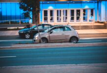 Fiat 500 jedzie nocą obok nowoczesnego, niebiesko podświetlonego biurowca