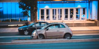 Fiat 500 jedzie nocą obok nowoczesnego, niebiesko podświetlonego biurowca