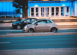 Fiat 500 jedzie nocą obok nowoczesnego, niebiesko podświetlonego biurowca