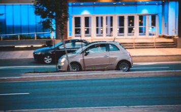 Skoda Citigo za grosze – czy mały mieszczuch to jeszcze rozsądny zakup w 2026 roku Fiat 500 jedzie nocą obok nowoczesnego, niebiesko podświetlonego biurowca