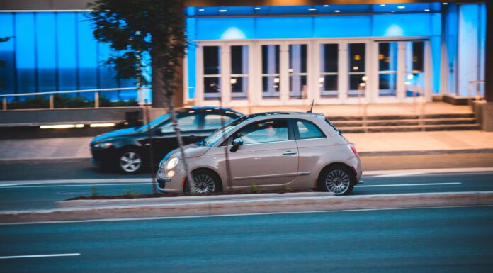 Fiat 500 jedzie nocą obok nowoczesnego, niebiesko podświetlonego biurowca