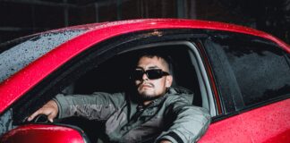 Młody kierowca w okularach słonecznych w czerwonym Hyundaiu i20 nocą