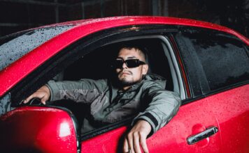 Młody kierowca w okularach słonecznych w czerwonym Hyundaiu i20 nocą