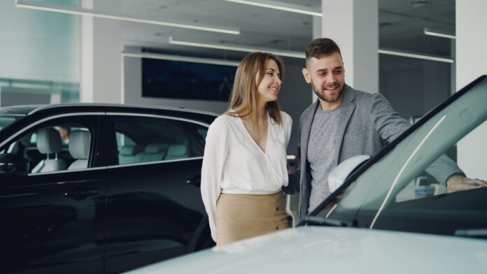 Uśmiechnięta para ogląda samochód Honda w salonie samochodowym Uśmiechnięta para ogląda samochód Honda w salonie samochodowym
