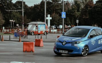 Tesla dla początkujących kierowców: czy to auto na co dzień? Niebieski samochód na asfaltowym torze wyścigowym w centrum miasta