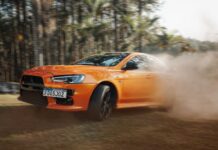 Pomarańczowe Lamborghini pędzące po zakurzonym torze