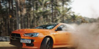 Pomarańczowe Lamborghini pędzące po zakurzonym torze