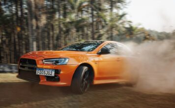 Pomarańczowe Lamborghini pędzące po zakurzonym torze