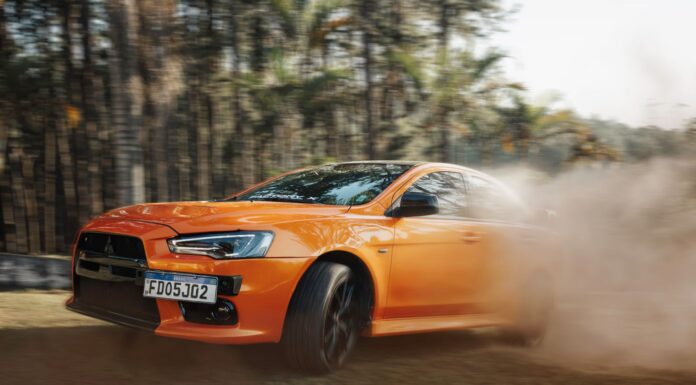 Pomarańczowe Lamborghini pędzące po zakurzonym torze