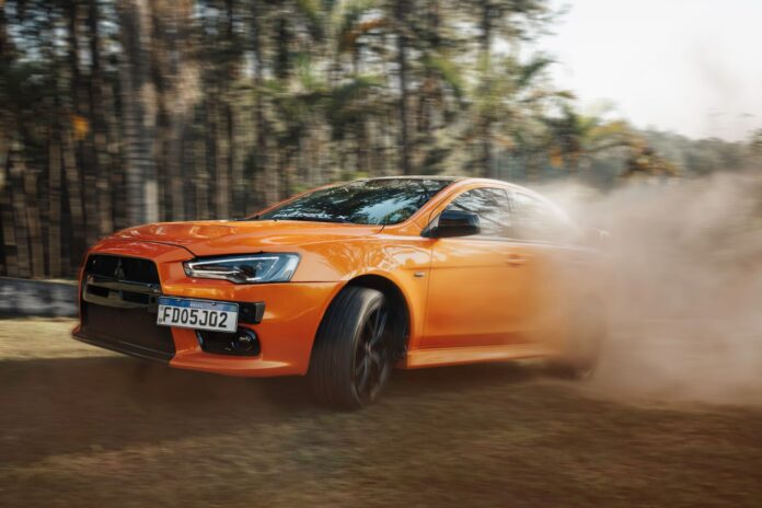 Pomarańczowe Lamborghini pędzące po zakurzonym torze