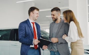 Uśmiechnięta para kupuje nowego Hyundaia u sprzedawcy w salonie