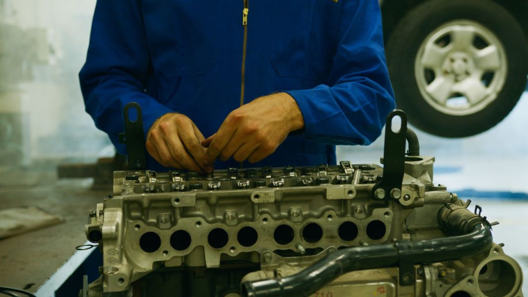 Mechanik naprawiający silnik Forda w warsztacie